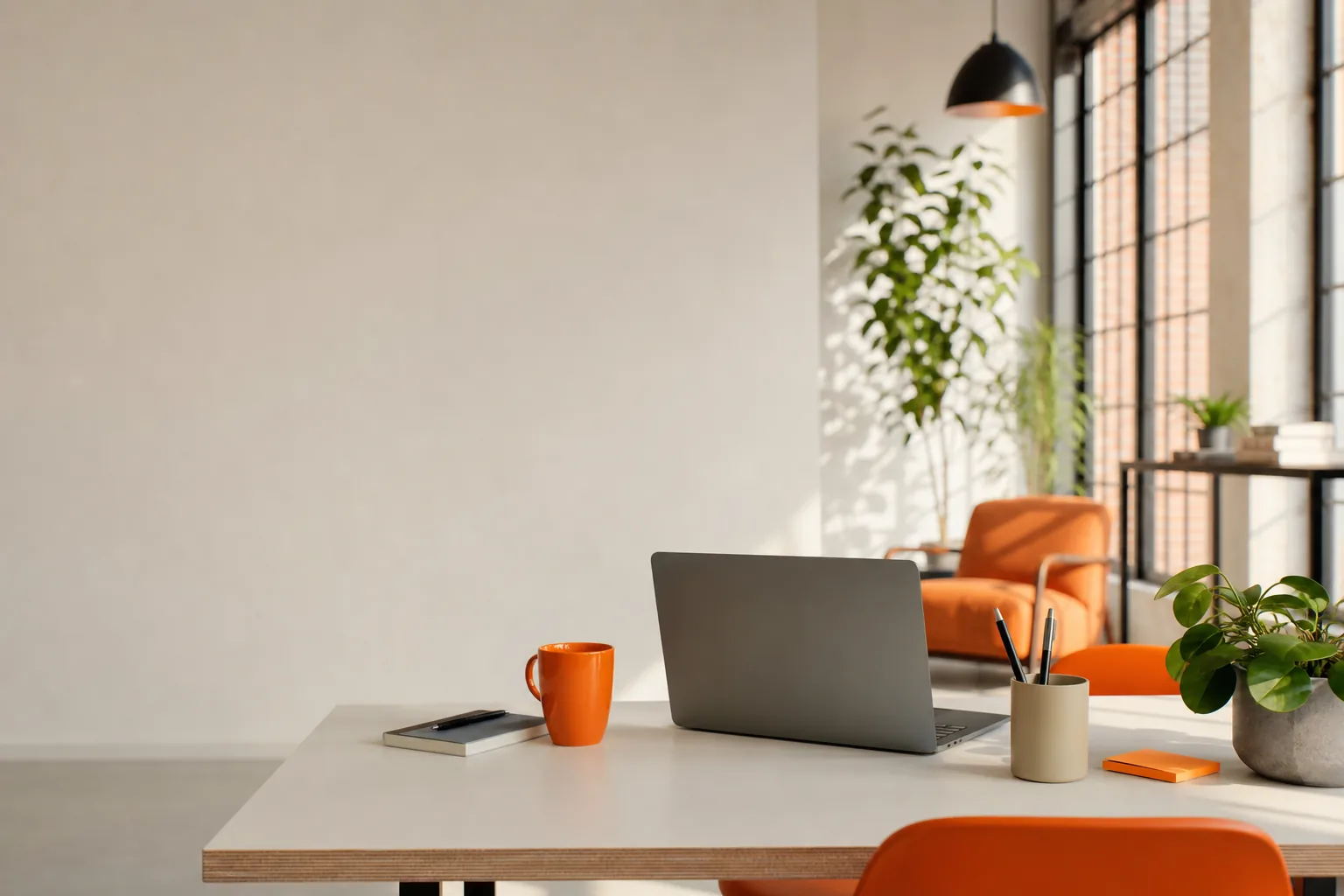 Minimalistisk skrivebord med laptop, orange kaffekop og potteplanter i et lyst kontor