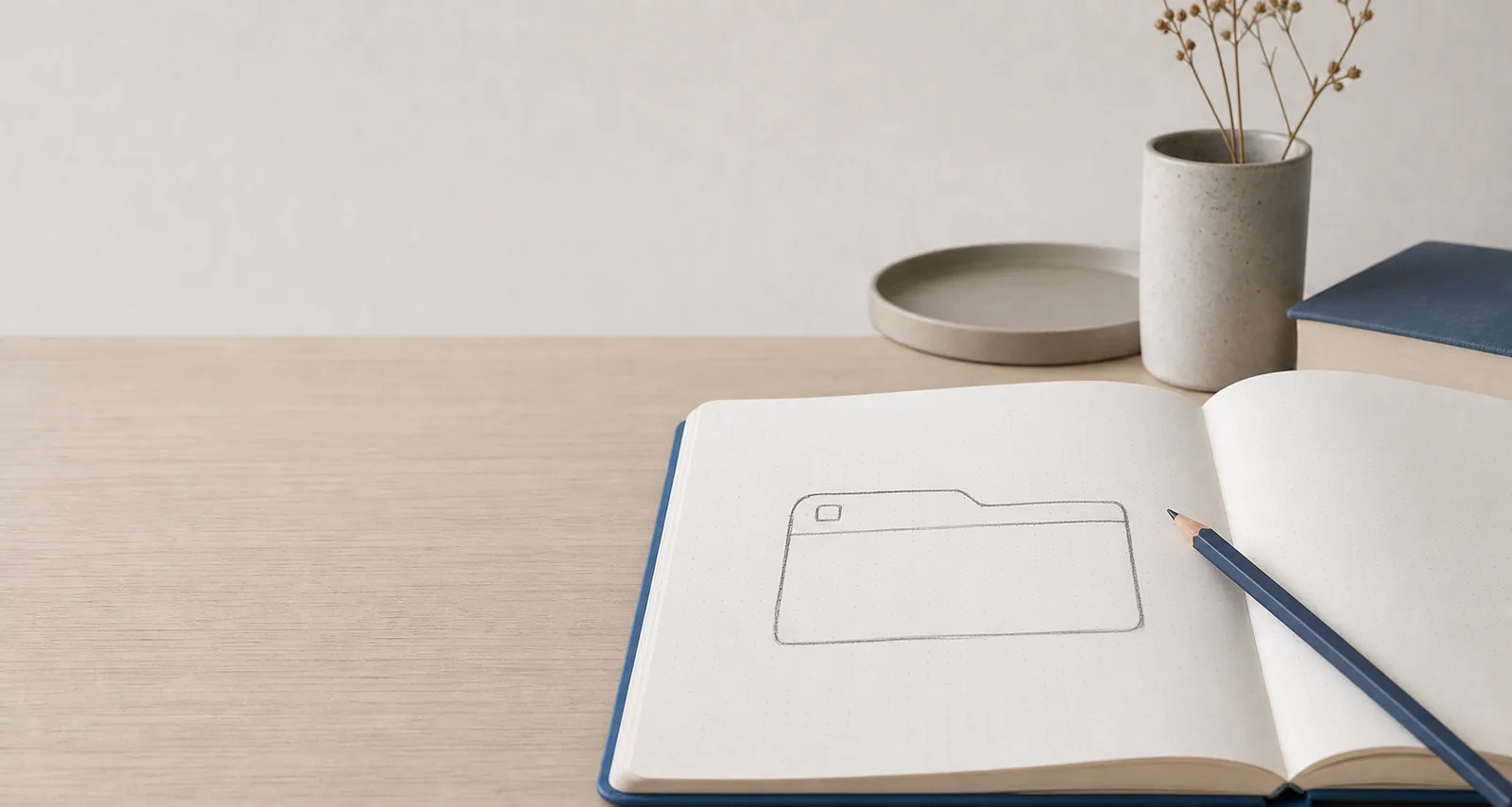 En åben notesbog viser tegning af en tablet enhed på minimalistisk skrivebordsopsætning.